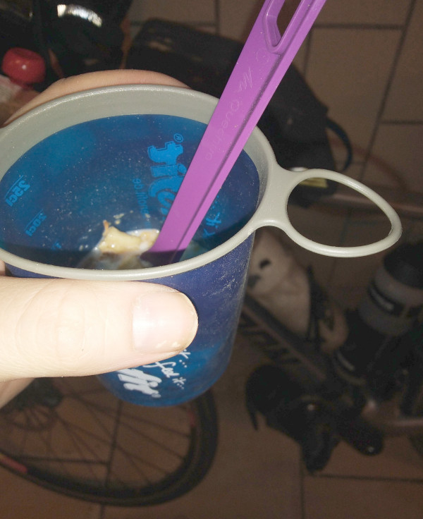 un verre souple avec du muesli et du lait devant vélo posé contre un mur